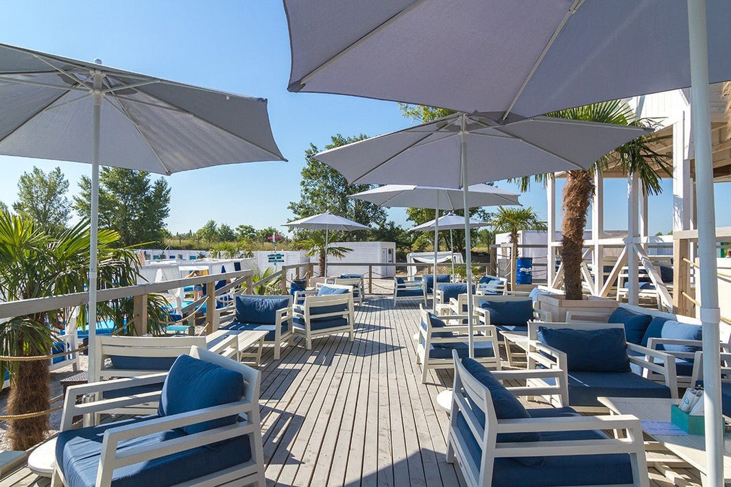 Exkluzív kültéri bútorok a Costes Beach Club teraszán, stílusos vízparti környezetben.
