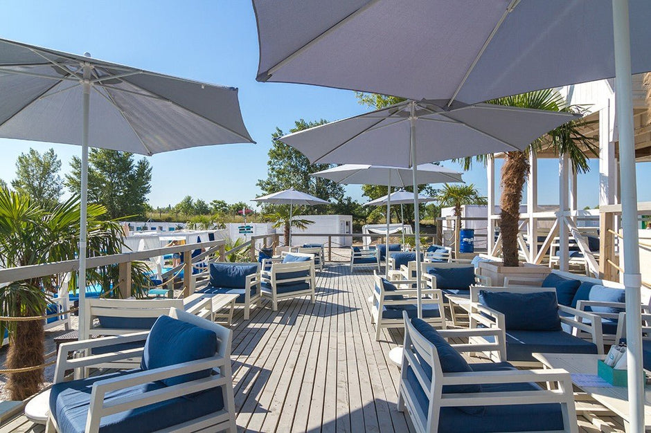 Exkluzív kültéri bútorok a Costes Beach Club teraszán, stílusos vízparti környezetben.