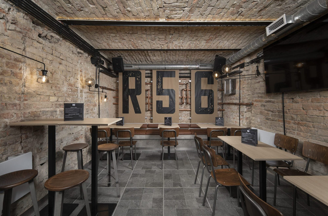 Loft stílusú gastropub berendezés bőr textúrájú székekkel és sötét tónusú asztalokkal az R56 belső terében.